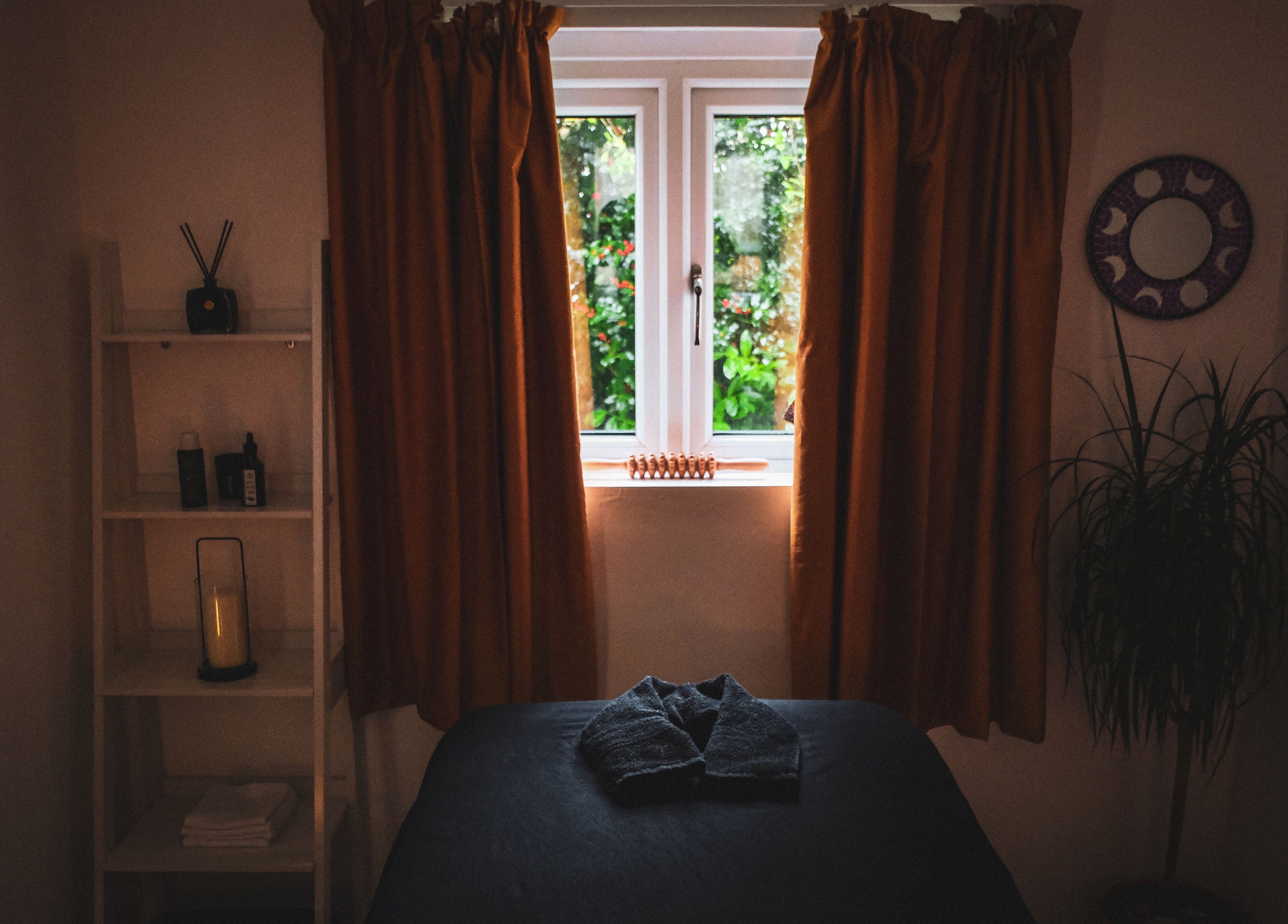 Serene massage room at Kaph Massage Therapies in Selling, England, GB with warm lighting and a window view.