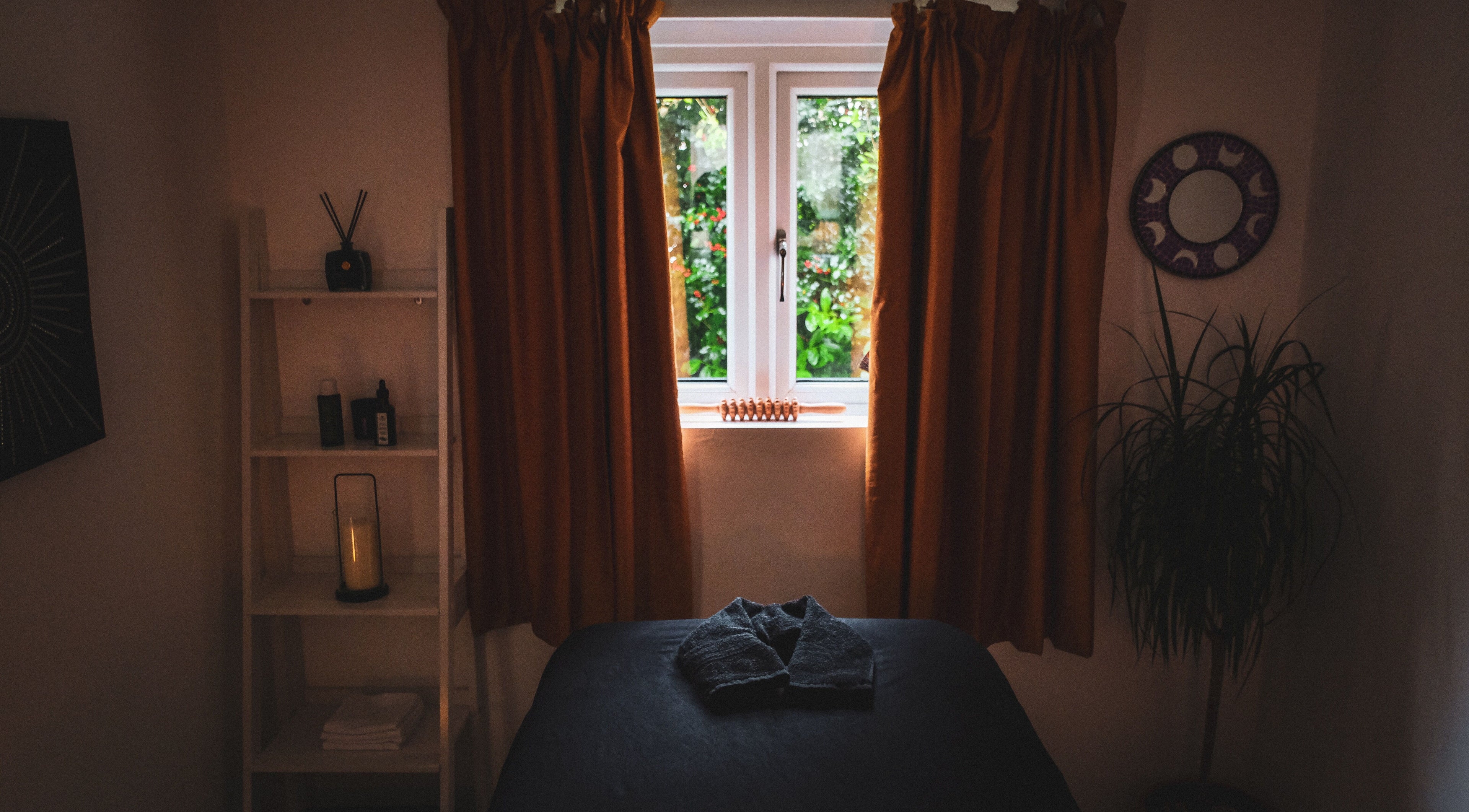 Serene massage room at Kaph Massage Therapies in Selling, England, GB with warm lighting and a window view.