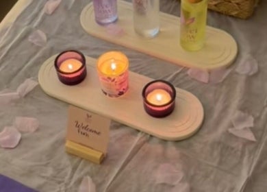 شموع مضاءة على طاولة مع منتجات Velvet Glow هوم سبا بالرياض، الرياض، SA تعزز الأجواء الهادئة.