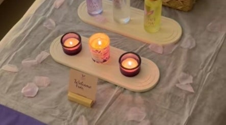 شموع مضاءة على طاولة مع منتجات Velvet Glow هوم سبا بالرياض، الرياض، SA تعزز الأجواء الهادئة.