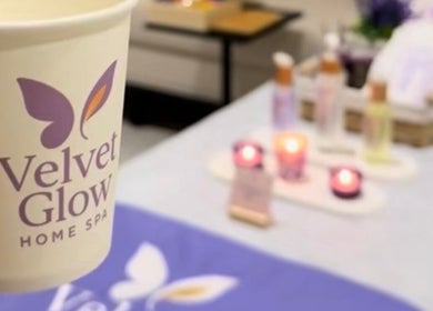 فنجان يحمل شعار Velvet Glow هوم سبا في الرياض، منطقة الرياض، السعودية، مع خلفية شمع وجو مريح.