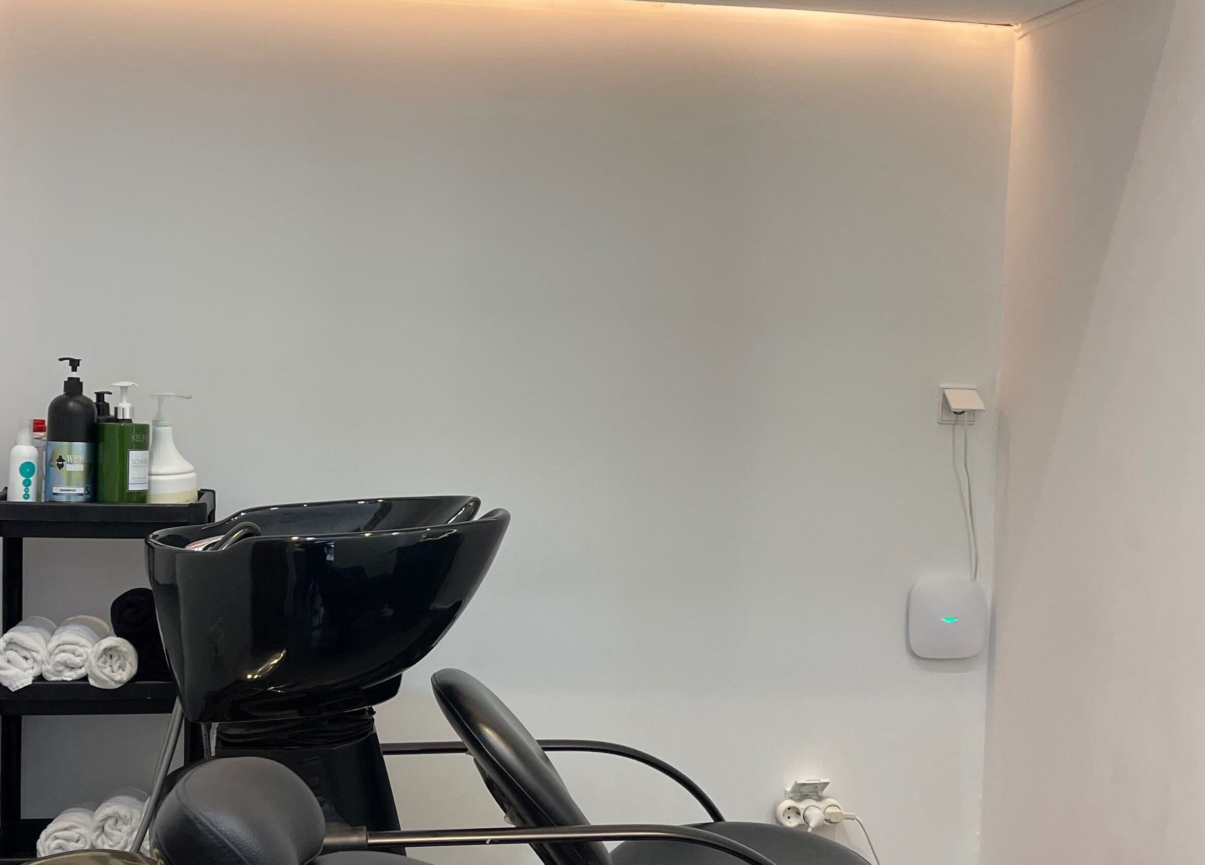 Área de lavagem moderna no salão Diego Leal, Lisboa, Lisboa, PT, com lavatório preto e produtos de beleza.