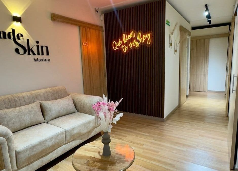 Sala de espera acogedora en Nudeskinwaxing, Medellín, Antioquia, CO, con sofá y decoración moderna.