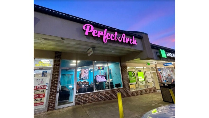 Brow Art 23 salon exterior during twilight in Reisterstown, Maryland, US with glowing signage.