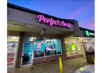 Brow Art 23 salon exterior during twilight in Reisterstown, Maryland, US with glowing signage.