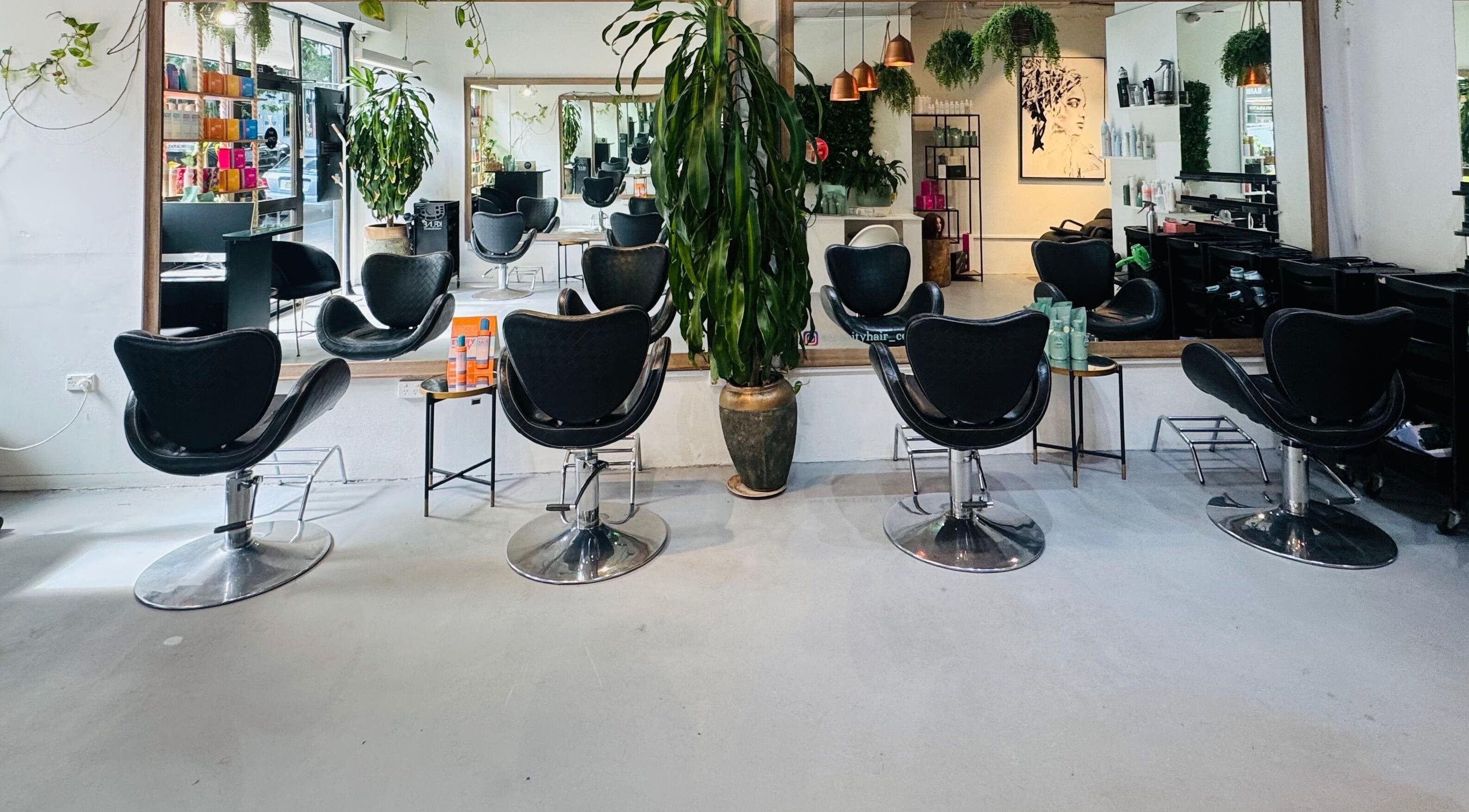 Modern salon interior of Hair by Sa in Surry Hills, New South Wales, AU with stylish chairs and lush plants.