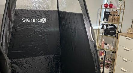 Spray tan tent setup at Ell’s Glow Studio in Galley Common, England, GB featuring Sienna products on shelves.