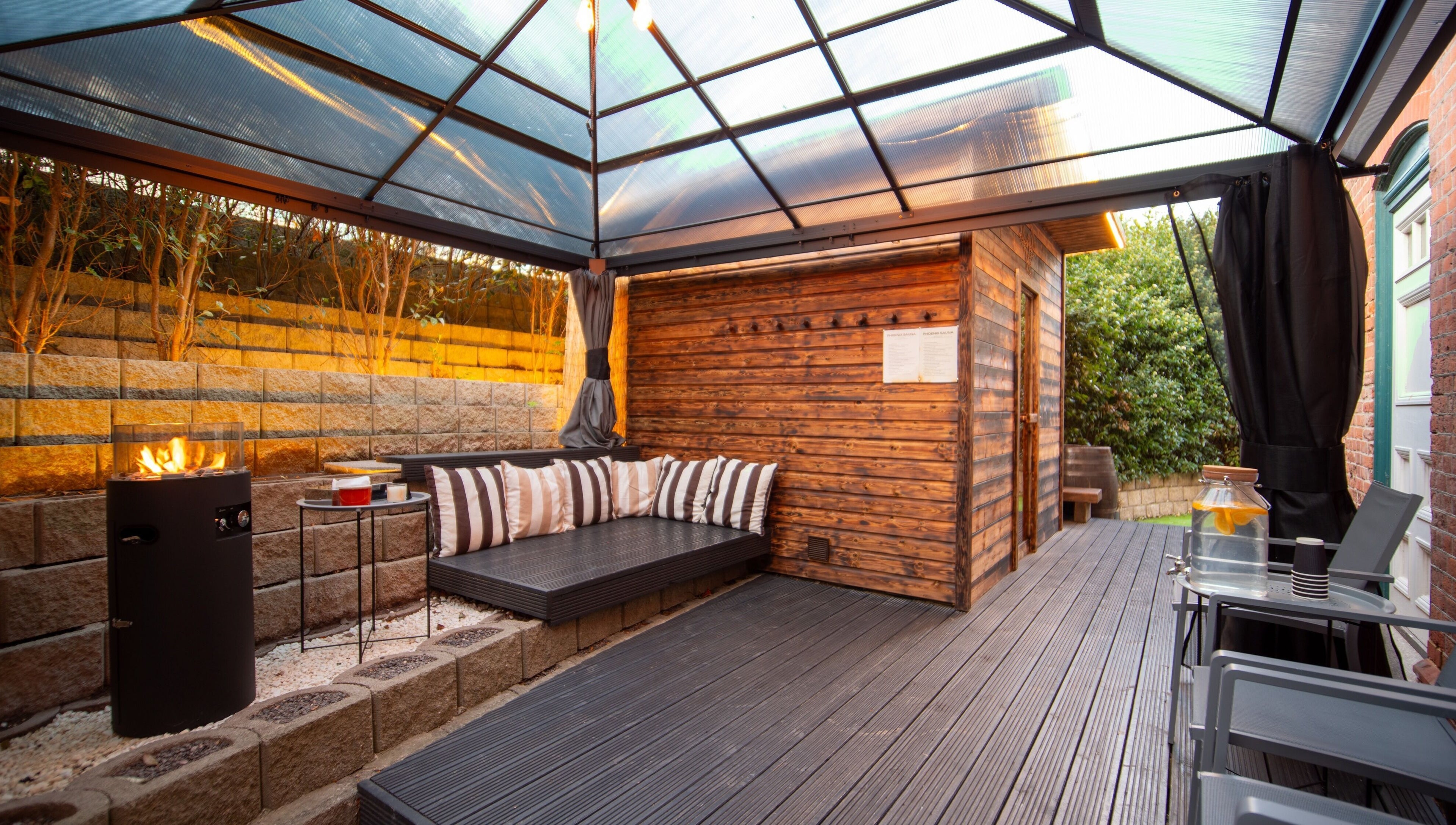 Cozy outdoor seating at Phoenix Burning Sauna in London, England, GB, with a modern fire pit.