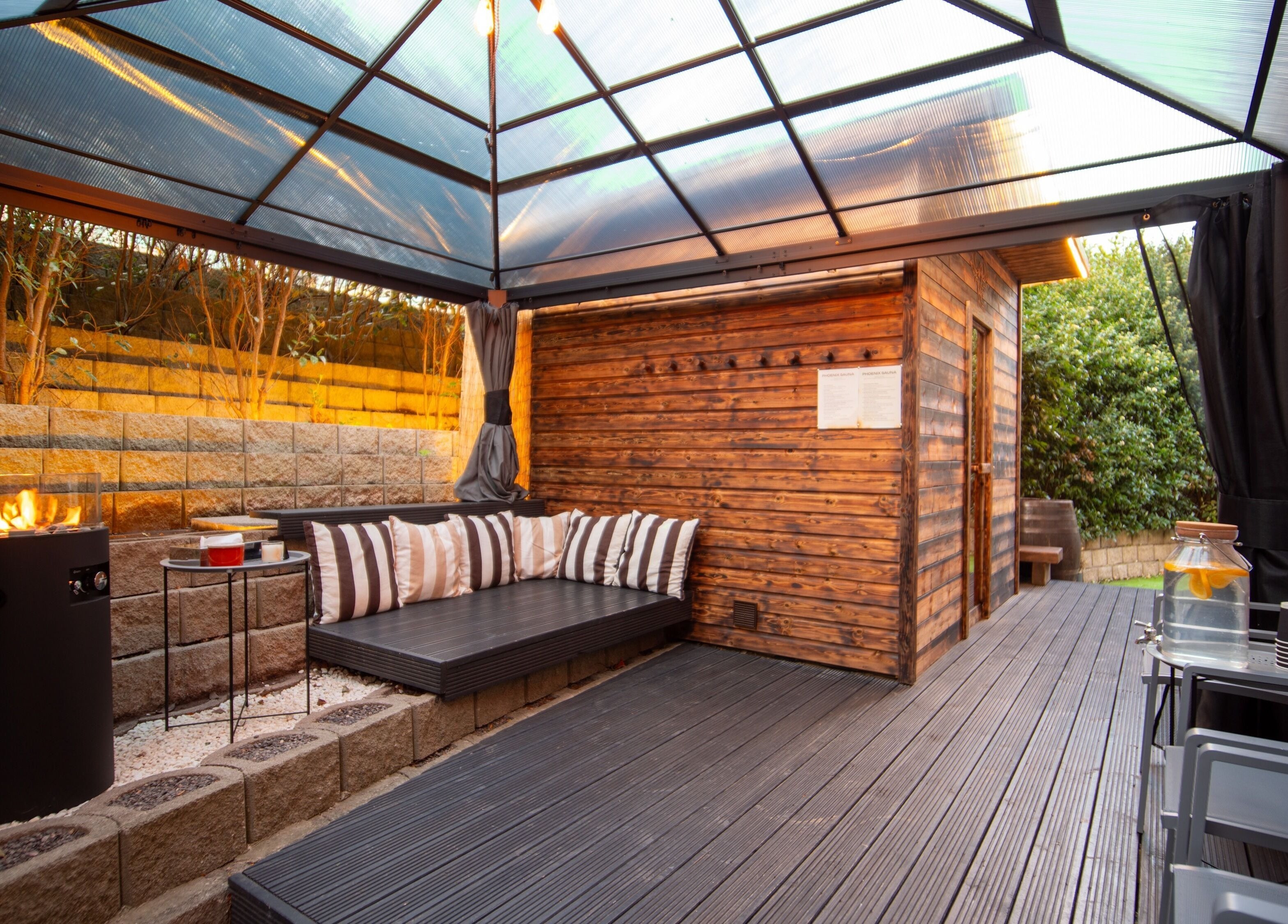 Cozy outdoor seating at Phoenix Burning Sauna in London, England, GB, with a modern fire pit.