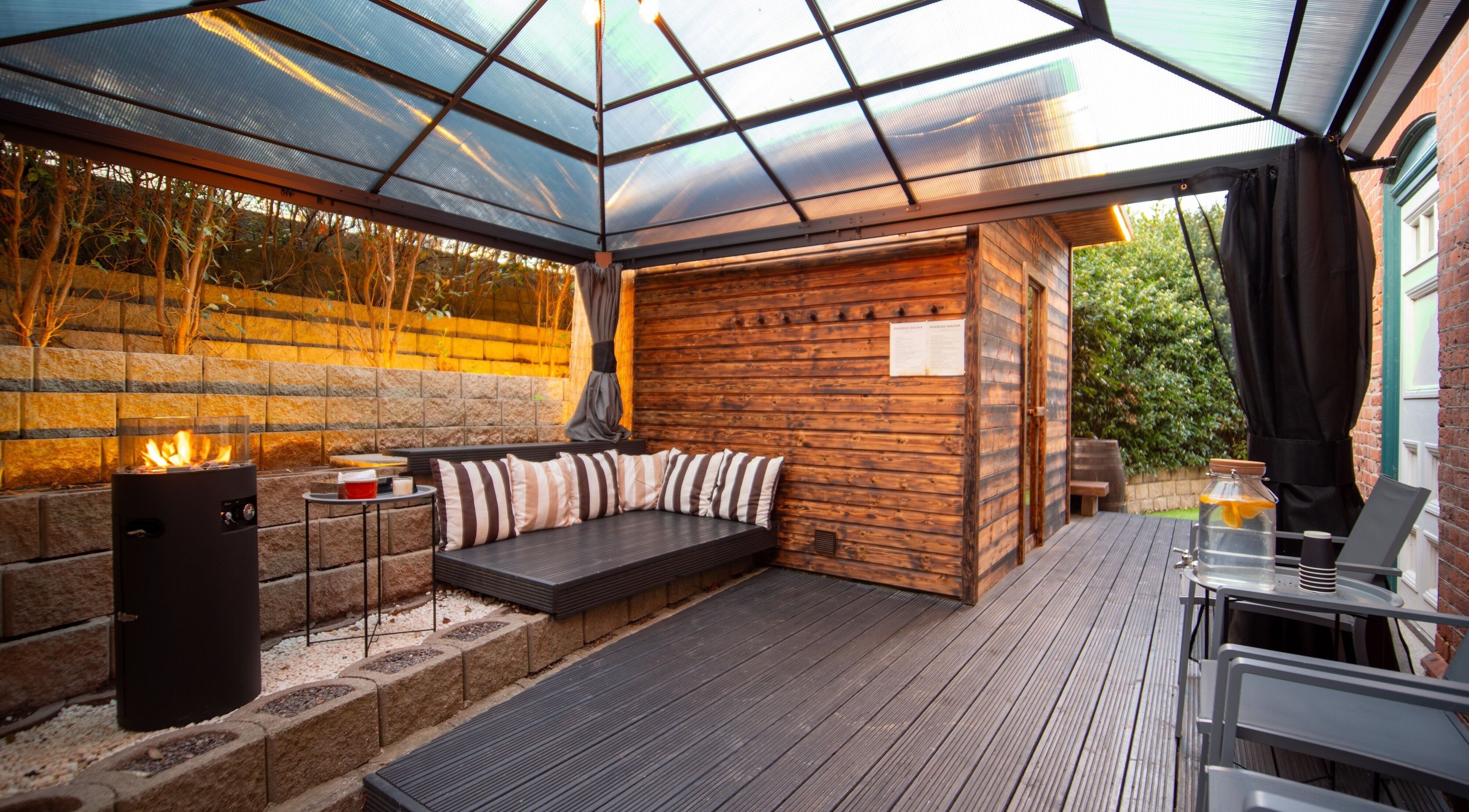 Cozy outdoor seating at Phoenix Burning Sauna in London, England, GB, with a modern fire pit.