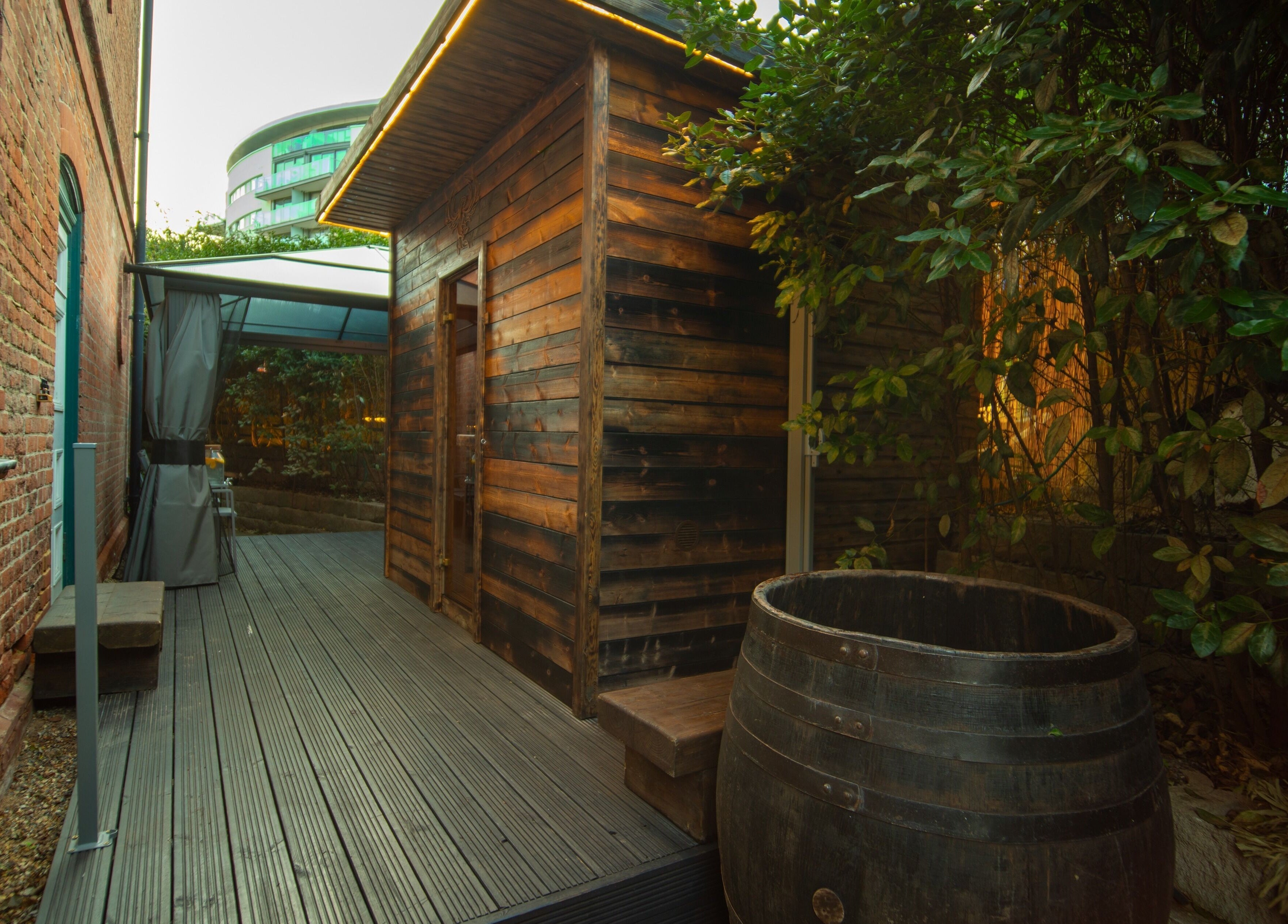 Wooden sauna exterior at Phoenix Burning Sauna, London, England, GB nestled in a serene garden setting.