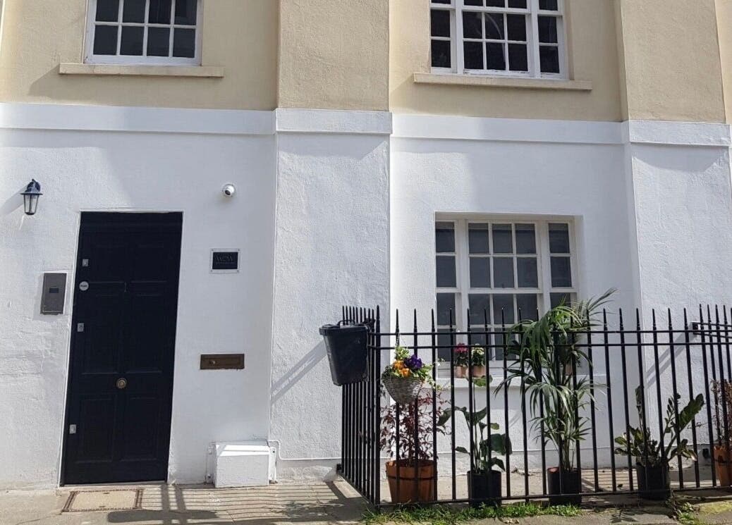 Charming facade of The Manicurist by CM in London, England, GB with a black door and floral decorations.