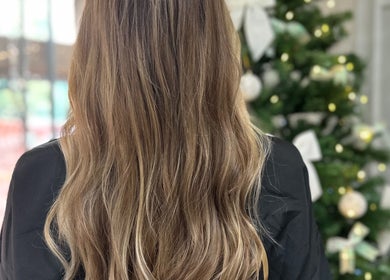 Capelli lunghi e ondulati presso GY Hair Style, Alessandria, Piemonte, IT, accanto a un albero di Natale decorato.