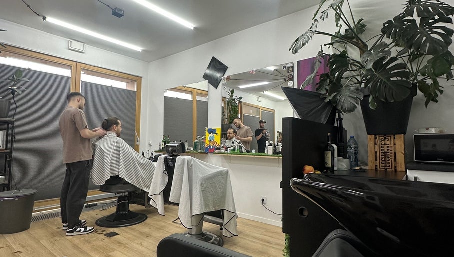 Wnętrze salonu Monkey w Warszawie, Województwo Mazowieckie, PL z klientem i fryzjerem w trakcie strzyżenia.