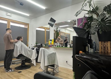 Wnętrze salonu Monkey w Warszawie, Województwo Mazowieckie, PL z klientem i fryzjerem w trakcie strzyżenia.