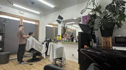 Wnętrze salonu Monkey w Warszawie, Województwo Mazowieckie, PL z klientem i fryzjerem w trakcie strzyżenia.