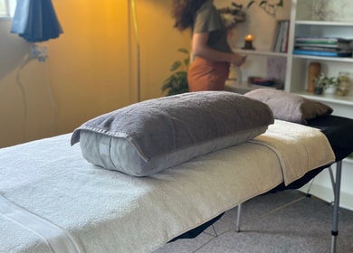Cozy massage table at Mumtra Doula, Gordonton, Waikato Region, NZ with soft lighting and shelves.