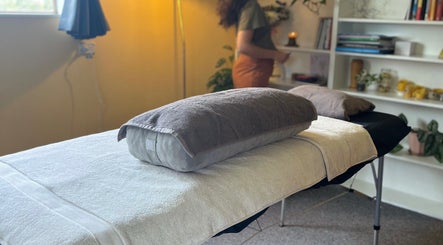 Cozy massage table at Mumtra Doula, Gordonton, Waikato Region, NZ with soft lighting and shelves.