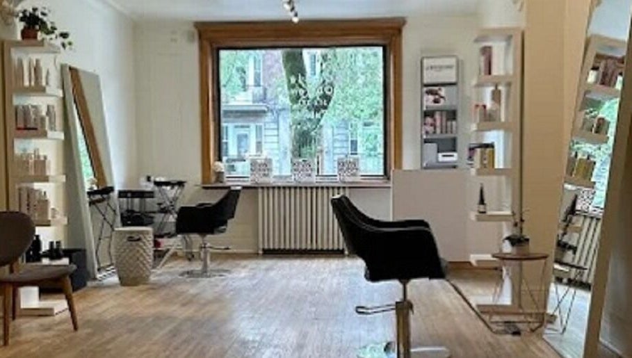 Espace élégant chez Karima Signature.ca, Montréal, Québec, CA, avec des chaises de salon et des étagères bien garnies.