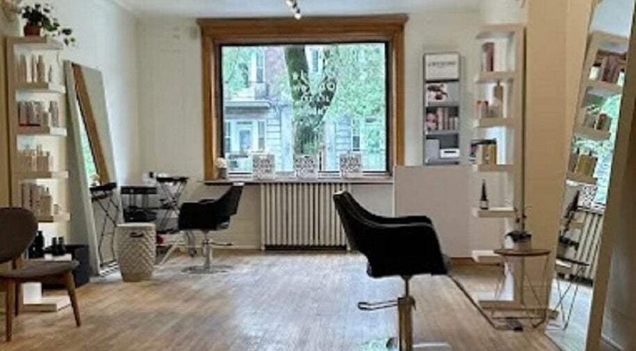 Espace élégant chez Karima Signature.ca, Montréal, Québec, CA, avec des chaises de salon et des étagères bien garnies.