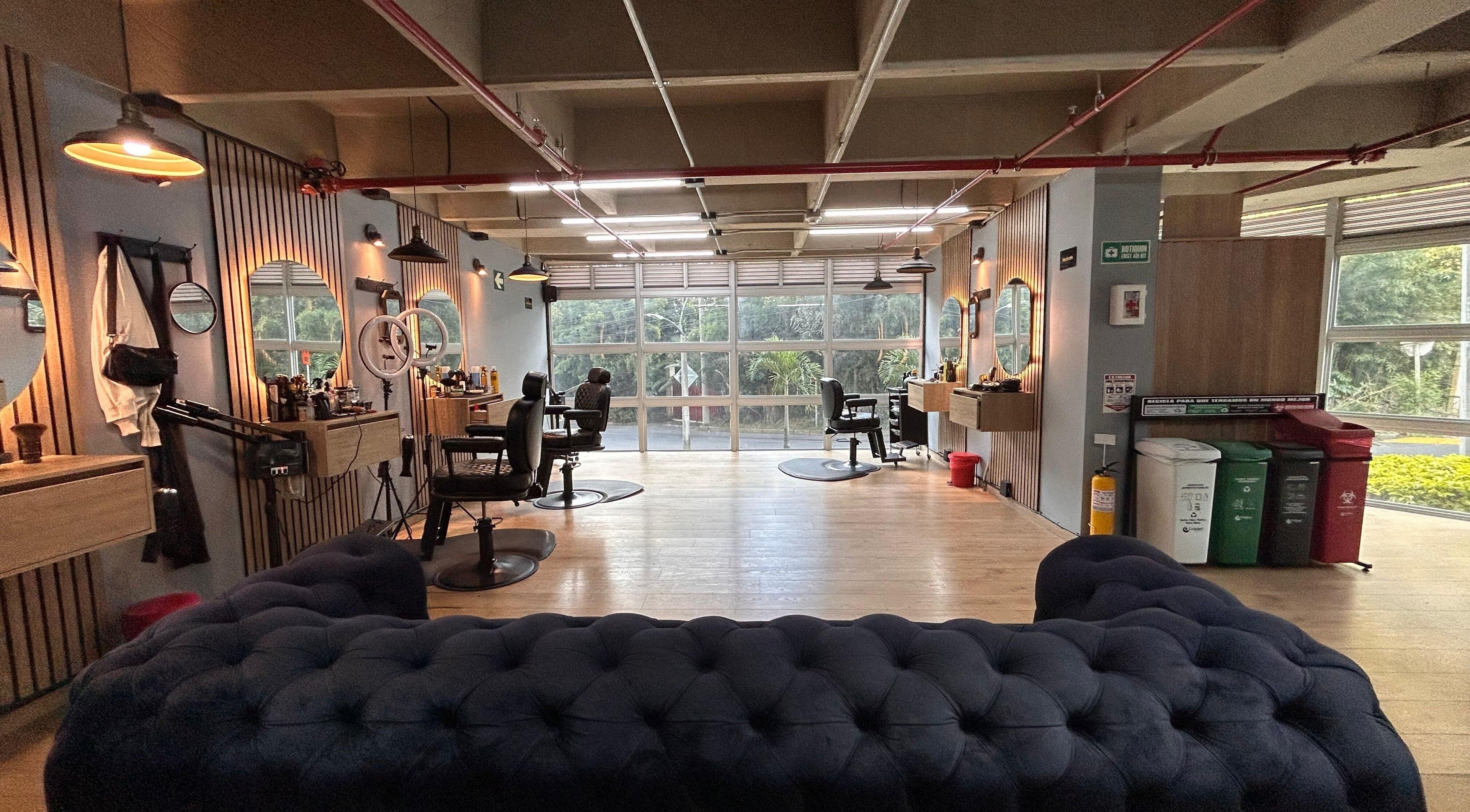 Interior acogedor de URUS BARBER SHOP en Antioquia, Antioquia, CO, con sillas de barbero y espejos iluminados.