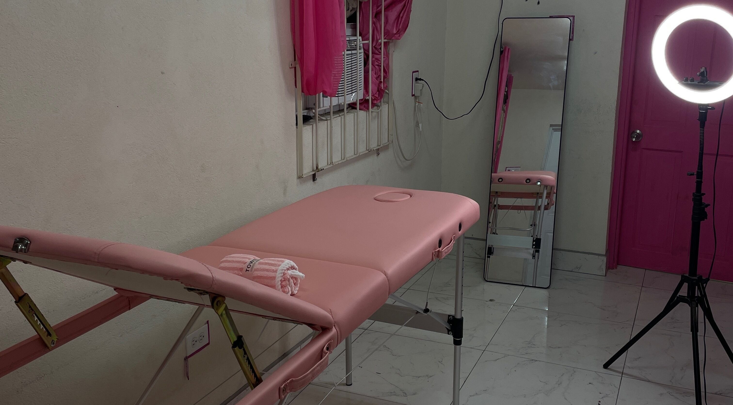 Cozy treatment room at Luxe Gleam Studio in Bridgetown, Saint Michael, BB with pink massage table and ring light.