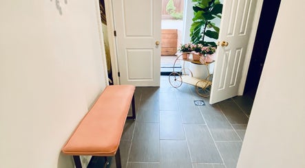 Warm and inviting entrance area at Spa Maluge in Hoboken, New Jersey, US with a plant and pink seating.