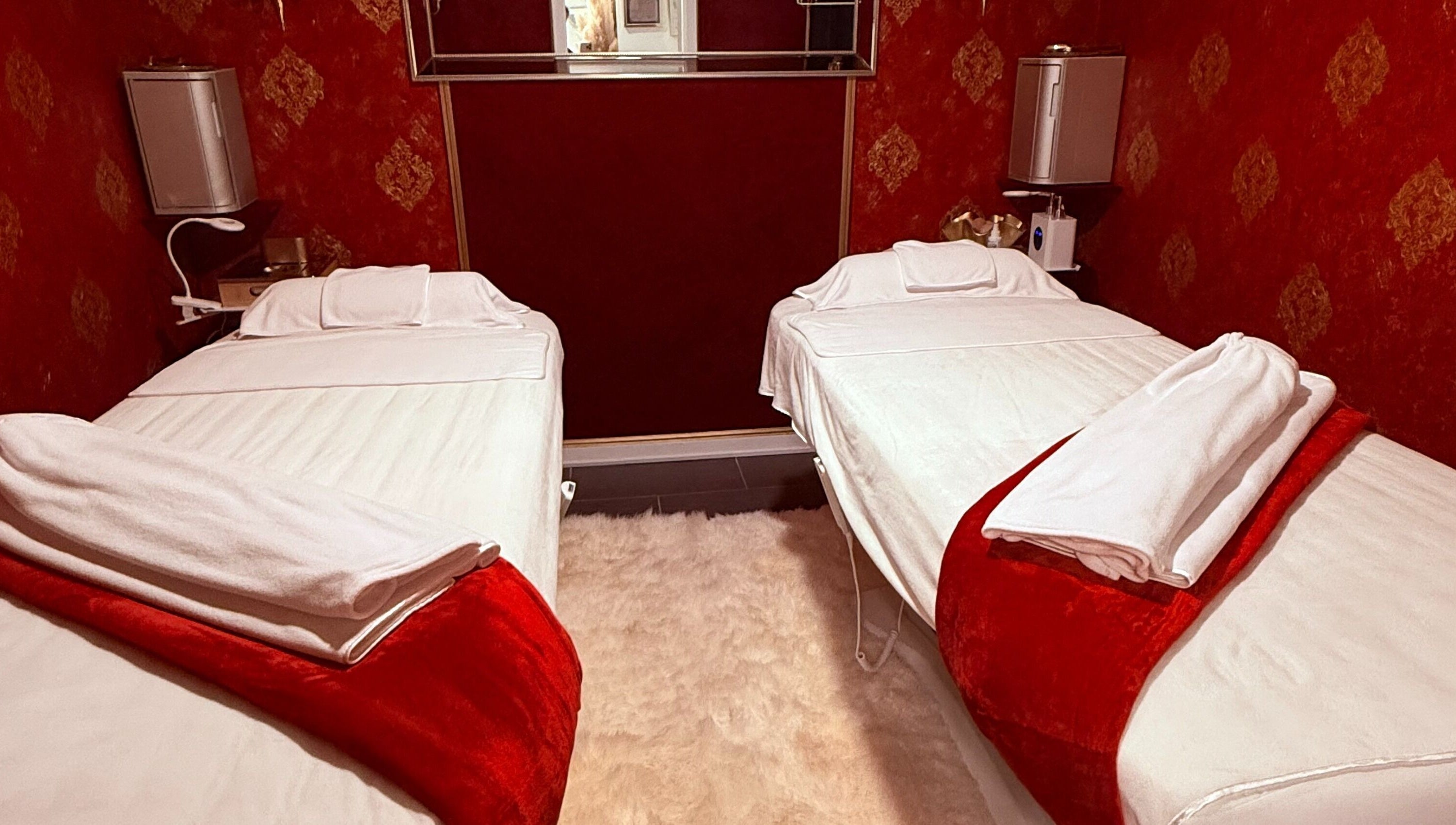 Relaxing red-themed massage room at Spa Maluge in Hoboken, New Jersey, US with two treatment beds.