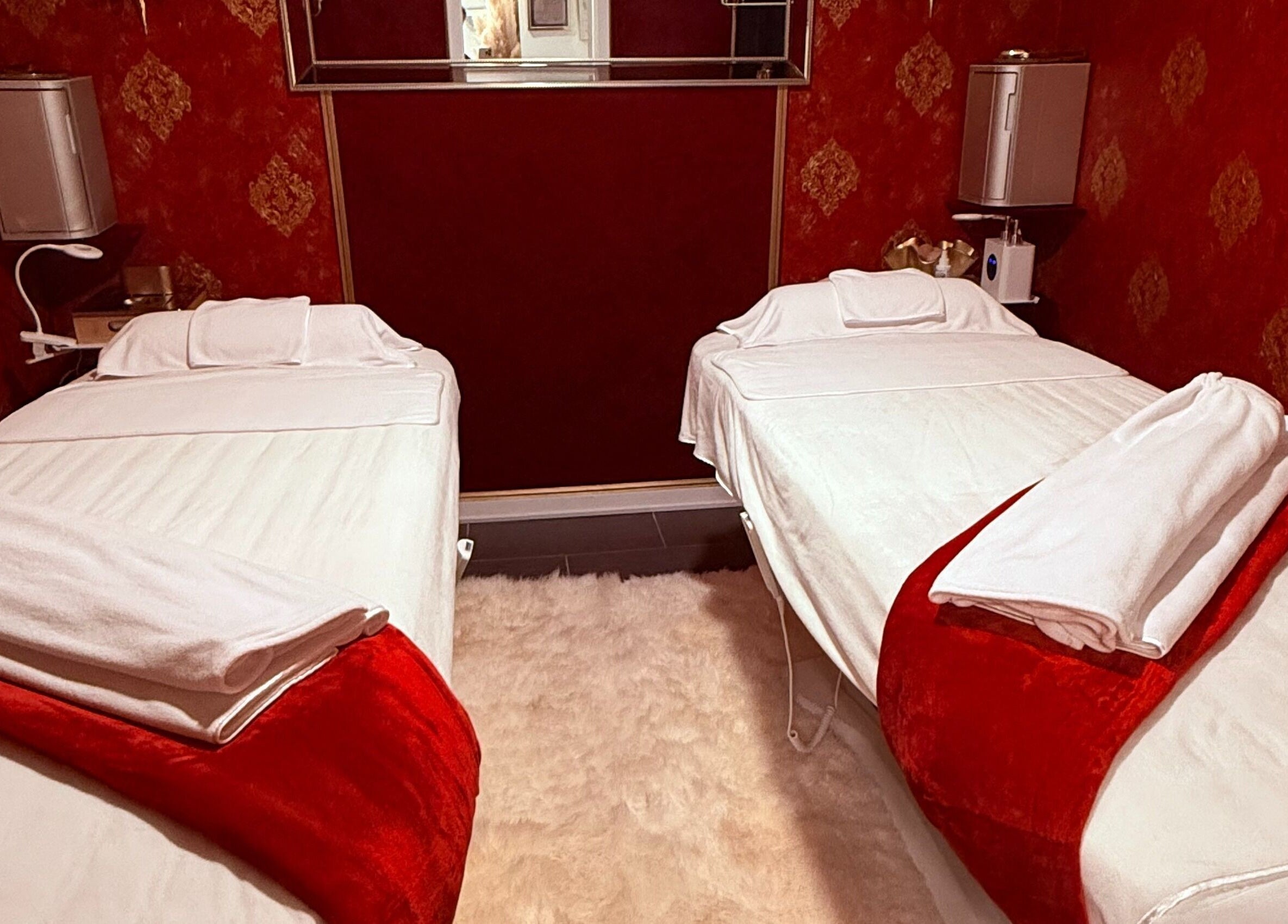 Relaxing red-themed massage room at Spa Maluge in Hoboken, New Jersey, US with two treatment beds.