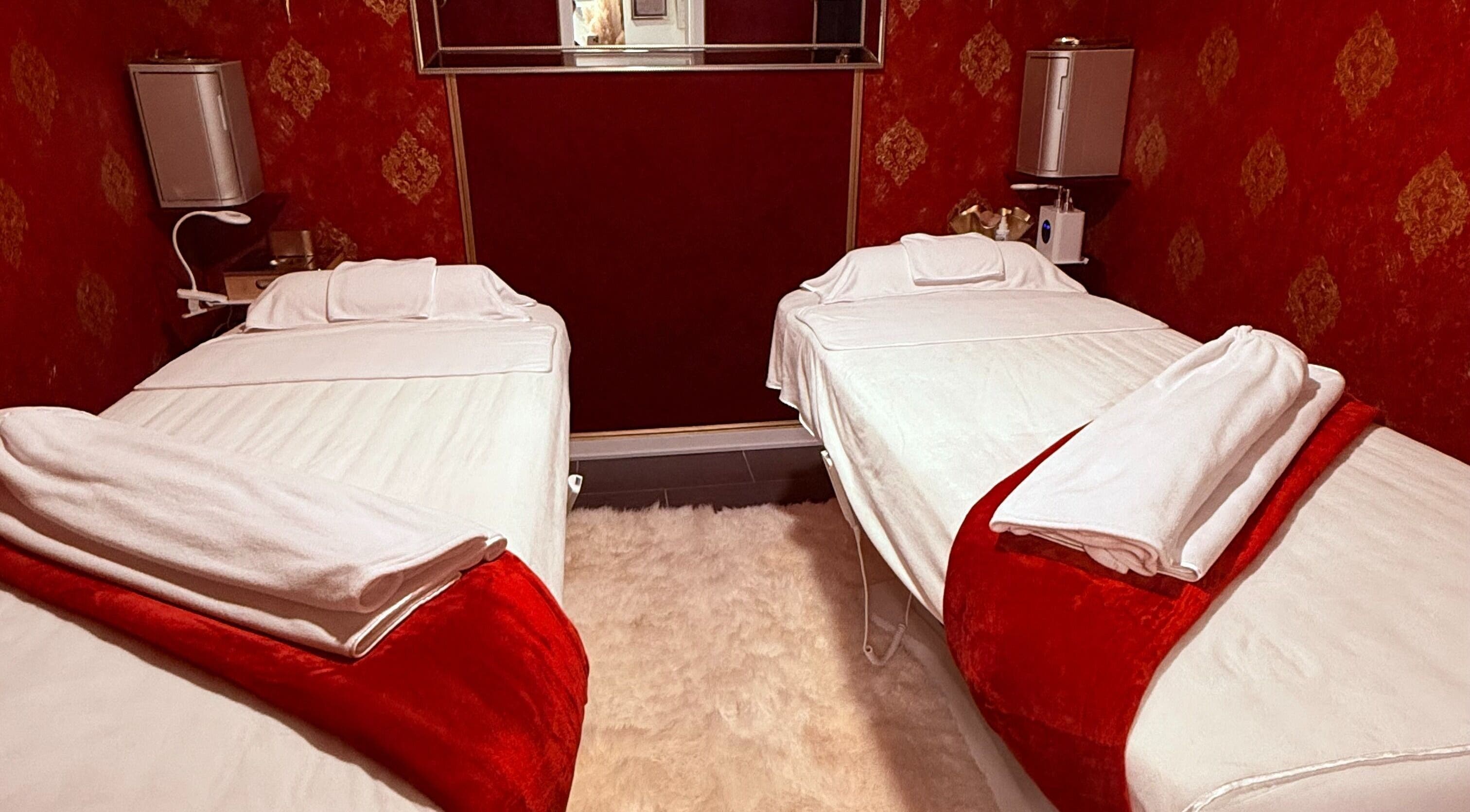 Relaxing red-themed massage room at Spa Maluge in Hoboken, New Jersey, US with two treatment beds.