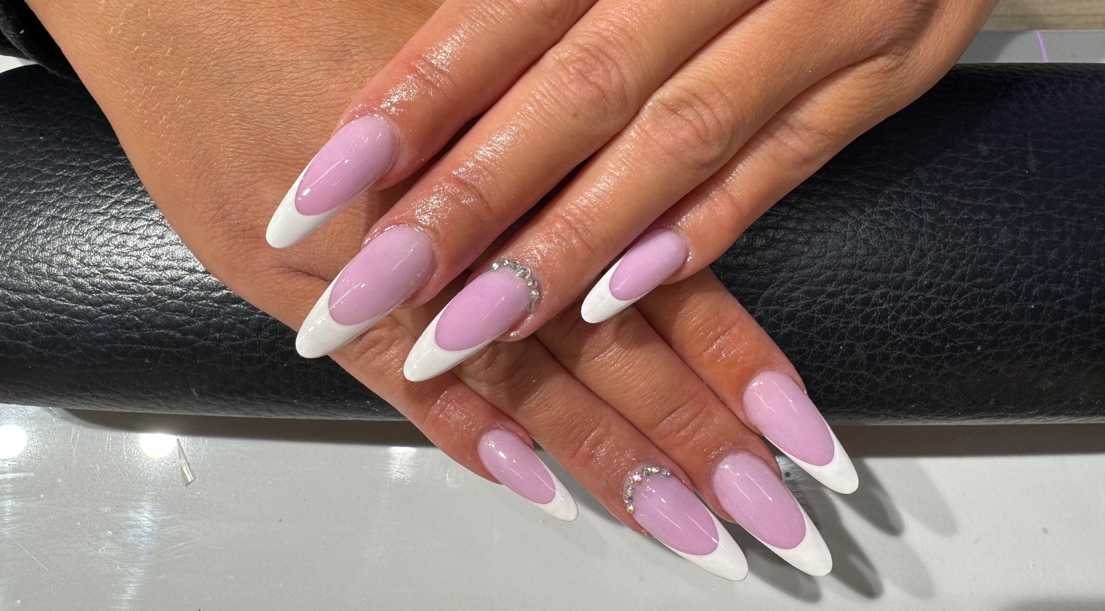 Stylish pink and white French manicure with rhinestones at Violet Nails Salon By Vi At Allertons Leeds, Leeds, England, GB.