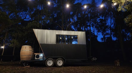 Unique modern cabin with lights at weThreshold in Woodend, Victoria, AU, highlighting serene forest surroundings.
