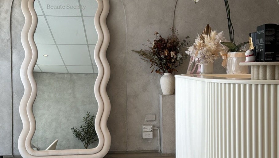 Elegant interior of Beaute Society in Rosebery, New South Wales, AU with a wavy mirror and floral arrangement.