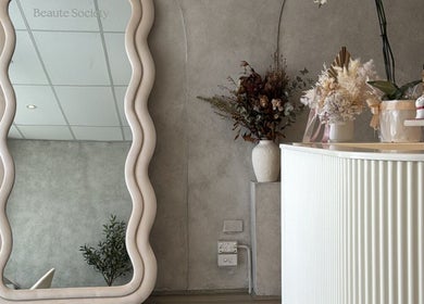 Elegant interior of Beaute Society in Rosebery, New South Wales, AU with a wavy mirror and floral arrangement.