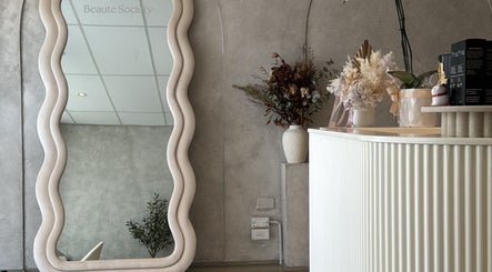 Elegant interior of Beaute Society in Rosebery, New South Wales, AU with a wavy mirror and floral arrangement.