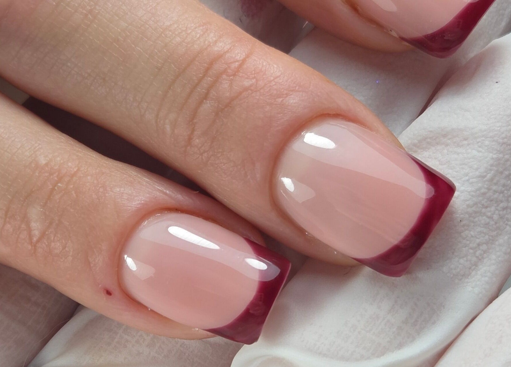 Gloss & Glitter in Petworth, England offers elegant burgundy French tip nails for a sophisticated look.