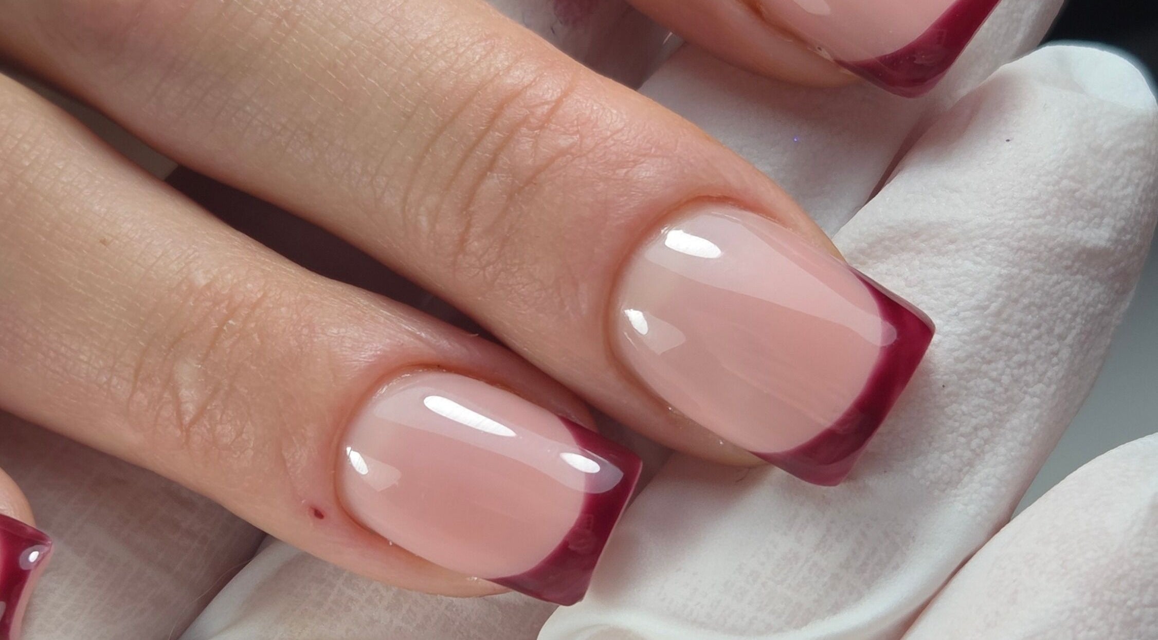 Gloss & Glitter in Petworth, England offers elegant burgundy French tip nails for a sophisticated look.