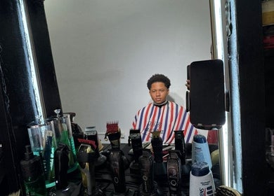 A client at Theblazebarbershop, Kingston, St. Andrew Parish, JM, in a barber chair with tools displayed.