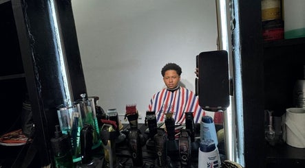 A client at Theblazebarbershop, Kingston, St. Andrew Parish, JM, in a barber chair with tools displayed.