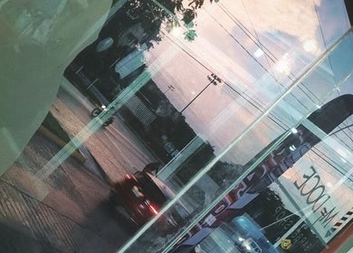 Vista urbana reflejada en la ventana de M DOCE BARBERIA, San Francisco De Campeche, Campeche, MX.