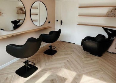 Salon chic d'Aiyra Signature à Crozet, Auvergne-rhône-alpes, FR, avec miroirs ronds et fauteuils noirs.