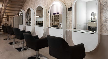 Chic salon stations at Maria, Athens, GR, with modern black chairs and oval mirrors.