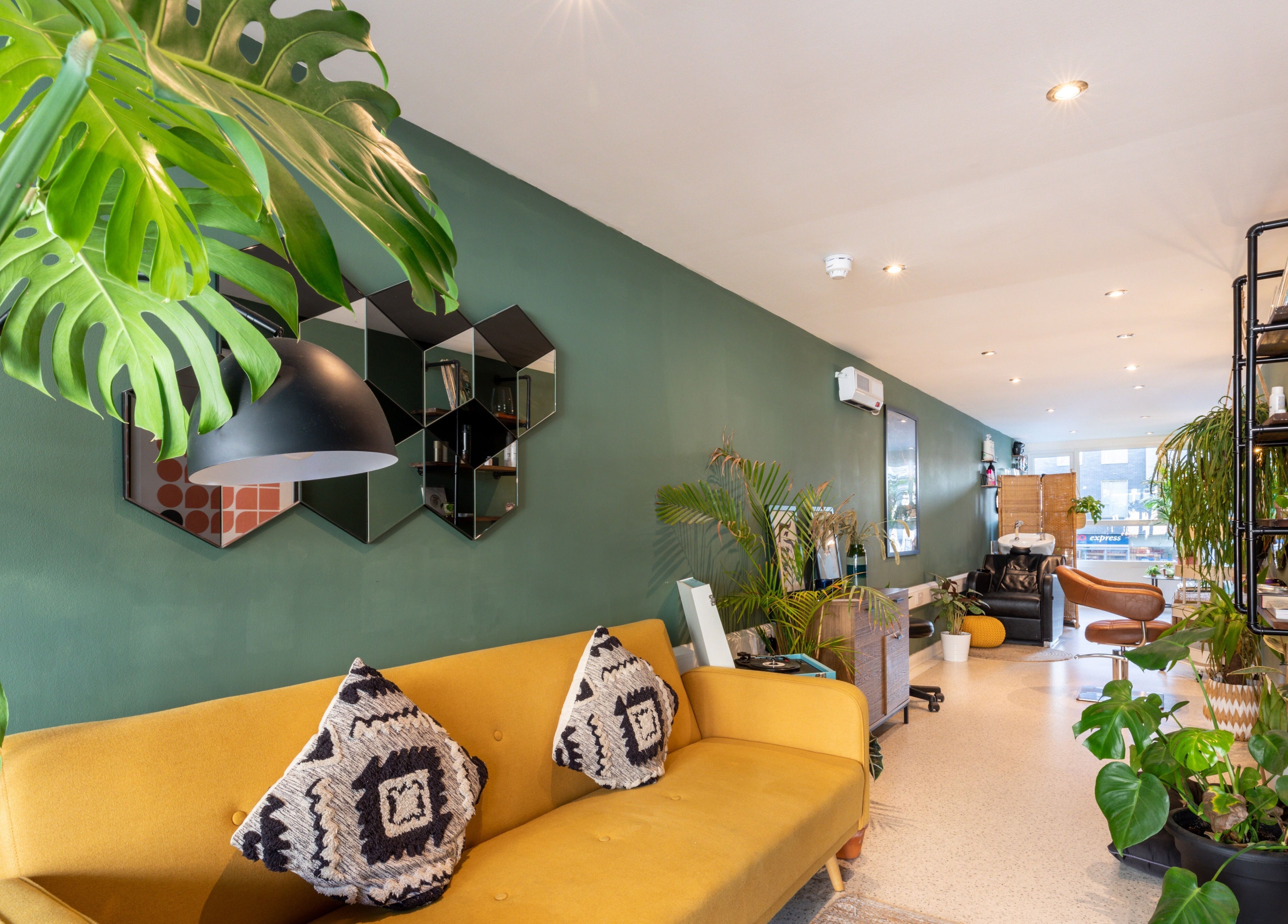 Bright and modern interior of Re:Create Hair Studio in London, England, GB with plants and stylish seating.