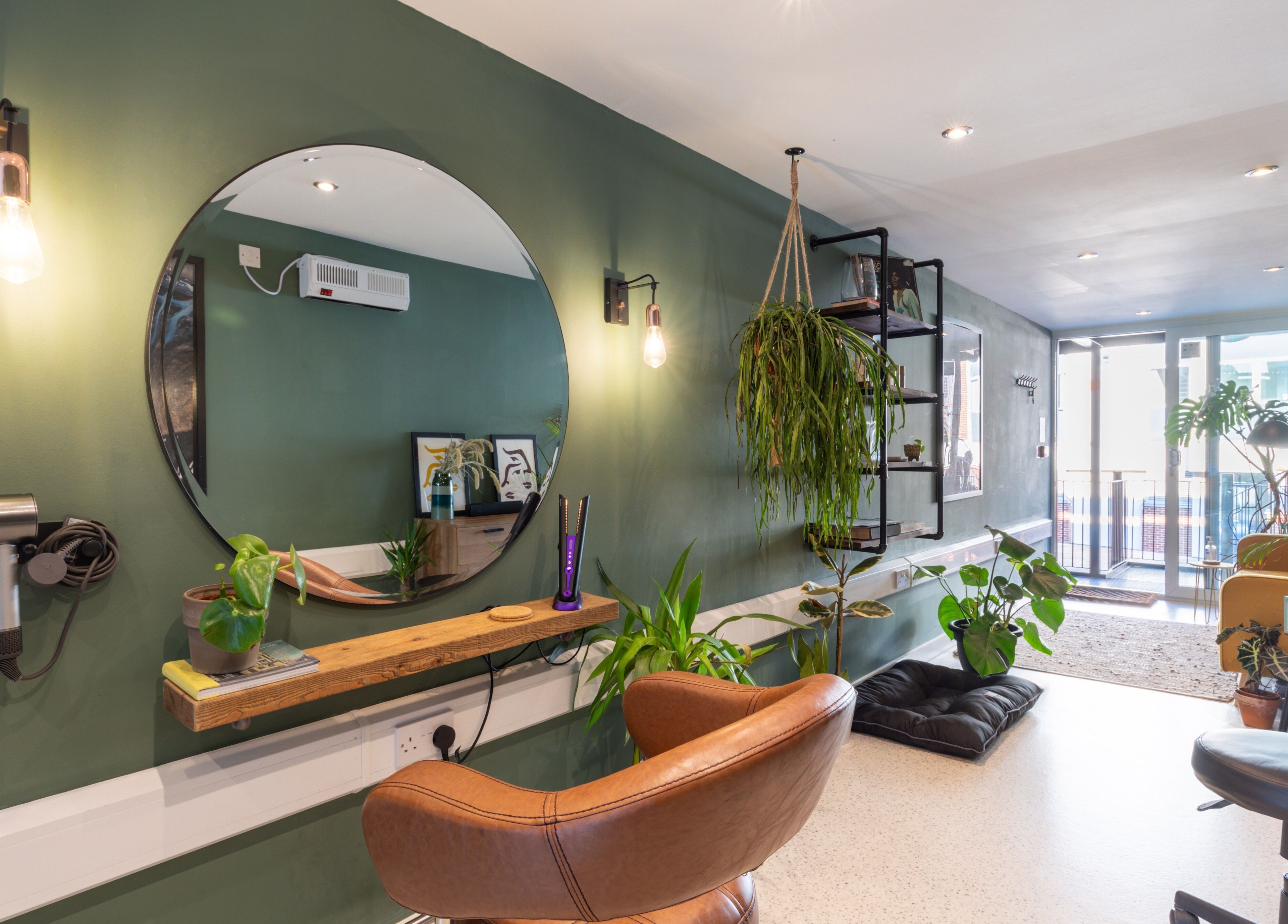 Chic interior of Re:Create Hair Studio in London, England, GB featuring green walls and lush plants.