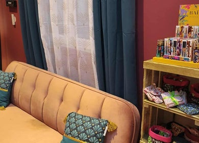 Salon accueillant de Pin-up'ement Belle à Elbeuf, Normandie, FR, avec canapé rose et étagère de produits.