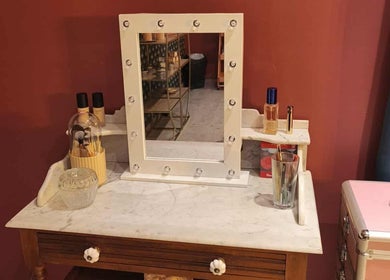 Coiffeuse élégante chez Pin-up'ement Belle, Elbeuf, Normandie, FR avec miroir orné et produits de beauté.