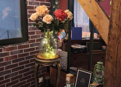 Vase illuminé avec fleurs à Pin-up'ement Belle, Elbeuf, Normandie, FR, sur un mur en briques.