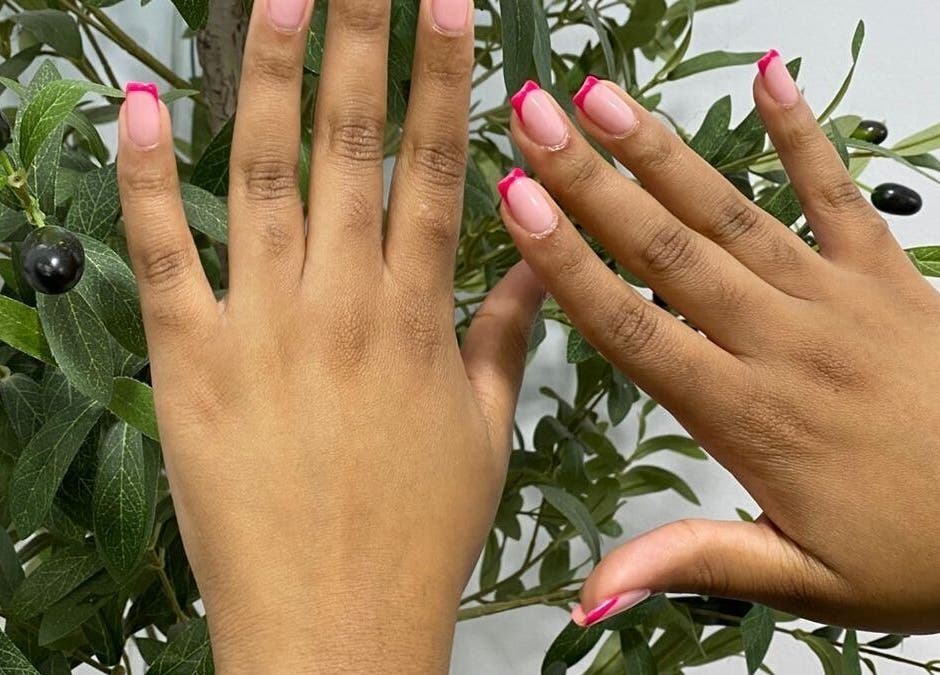 Hands with pink-tipped nails at Lyn's beauty studio in Sandton, Gauteng, ZA, showcasing elegant nail art.