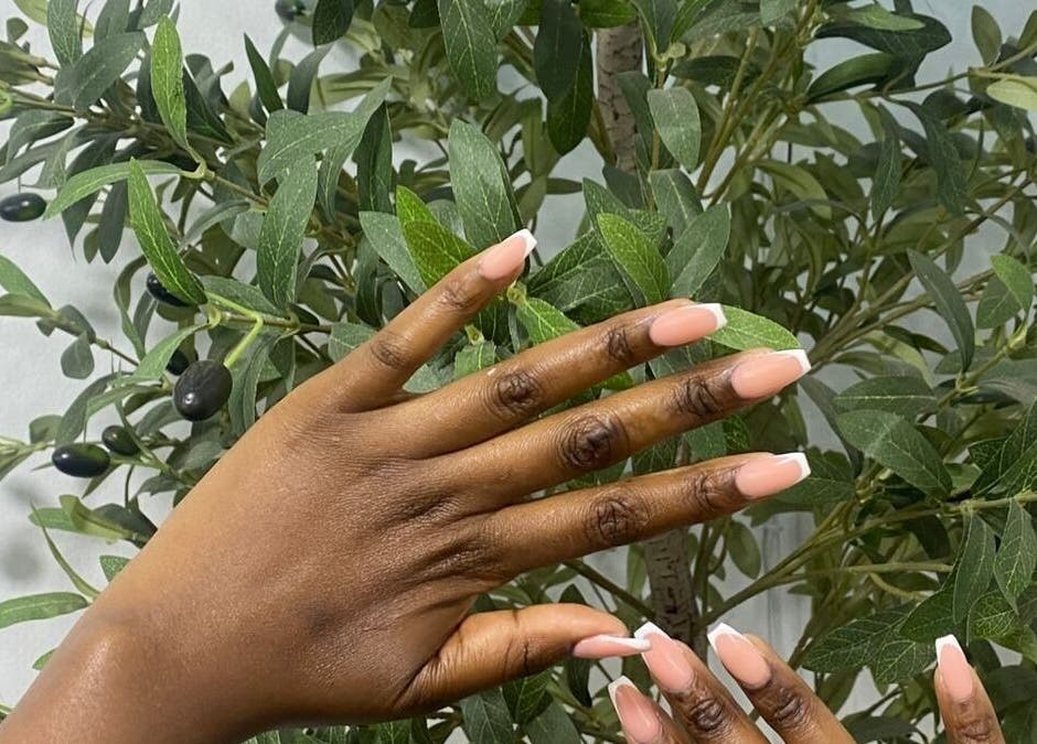 Stylish French manicure at Lyn's Beauty Studio in Sandton, Gauteng, ZA, set against a lush plant backdrop.