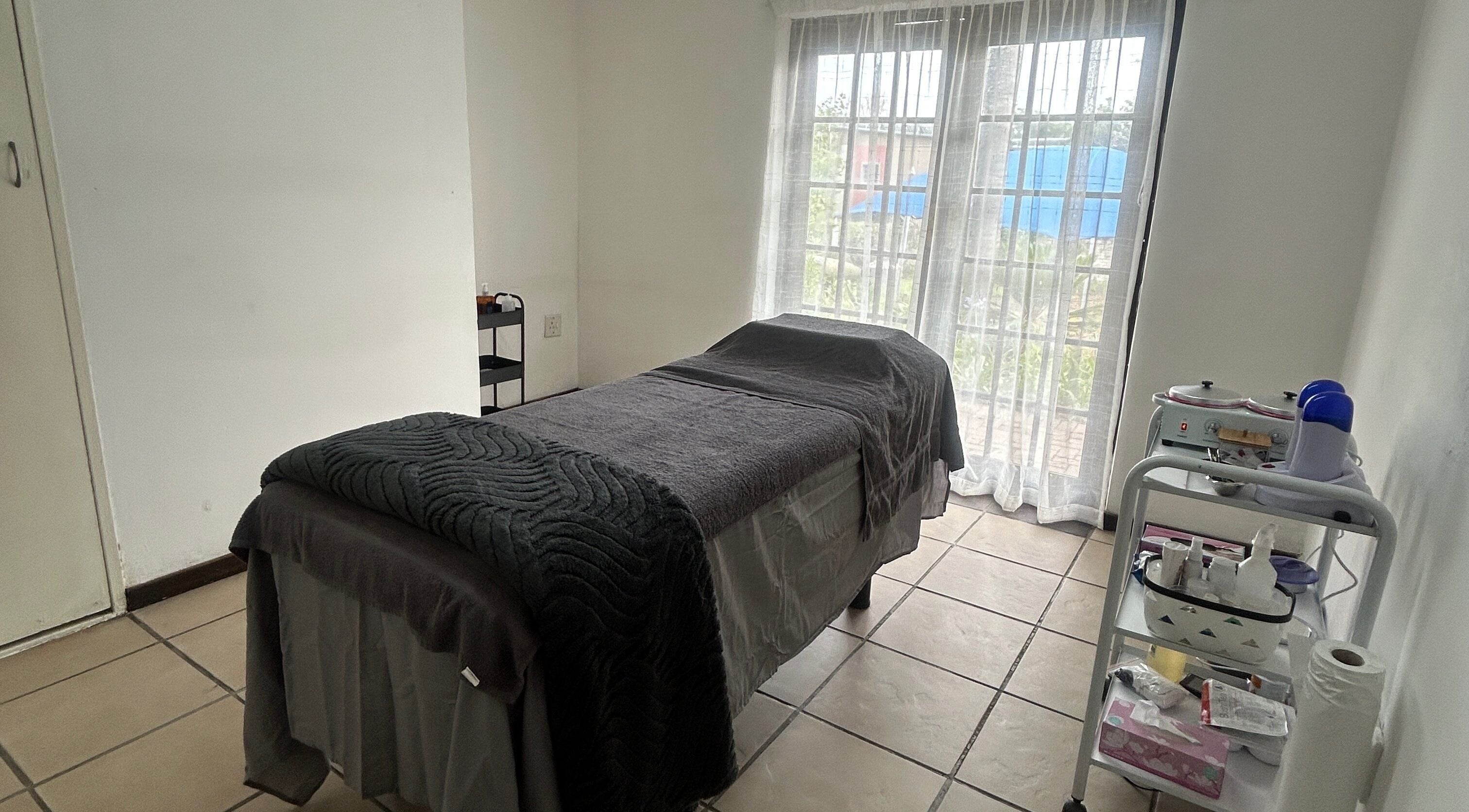 A tranquil treatment room at Beautifly Garden in Sandton, Gauteng, ZA, featuring a massage table and soft lighting.